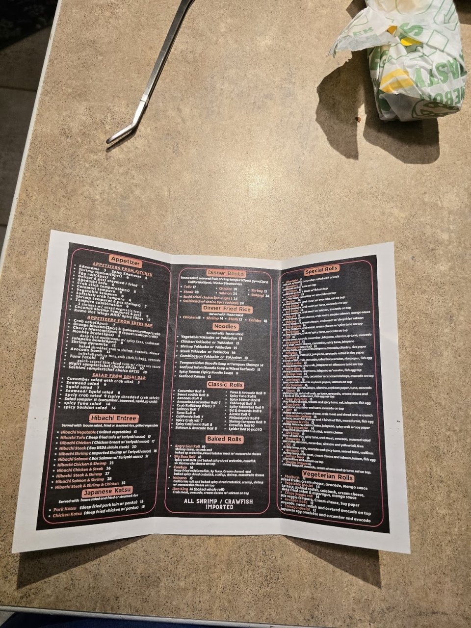 Close-up of a menu showing rolls and wine.